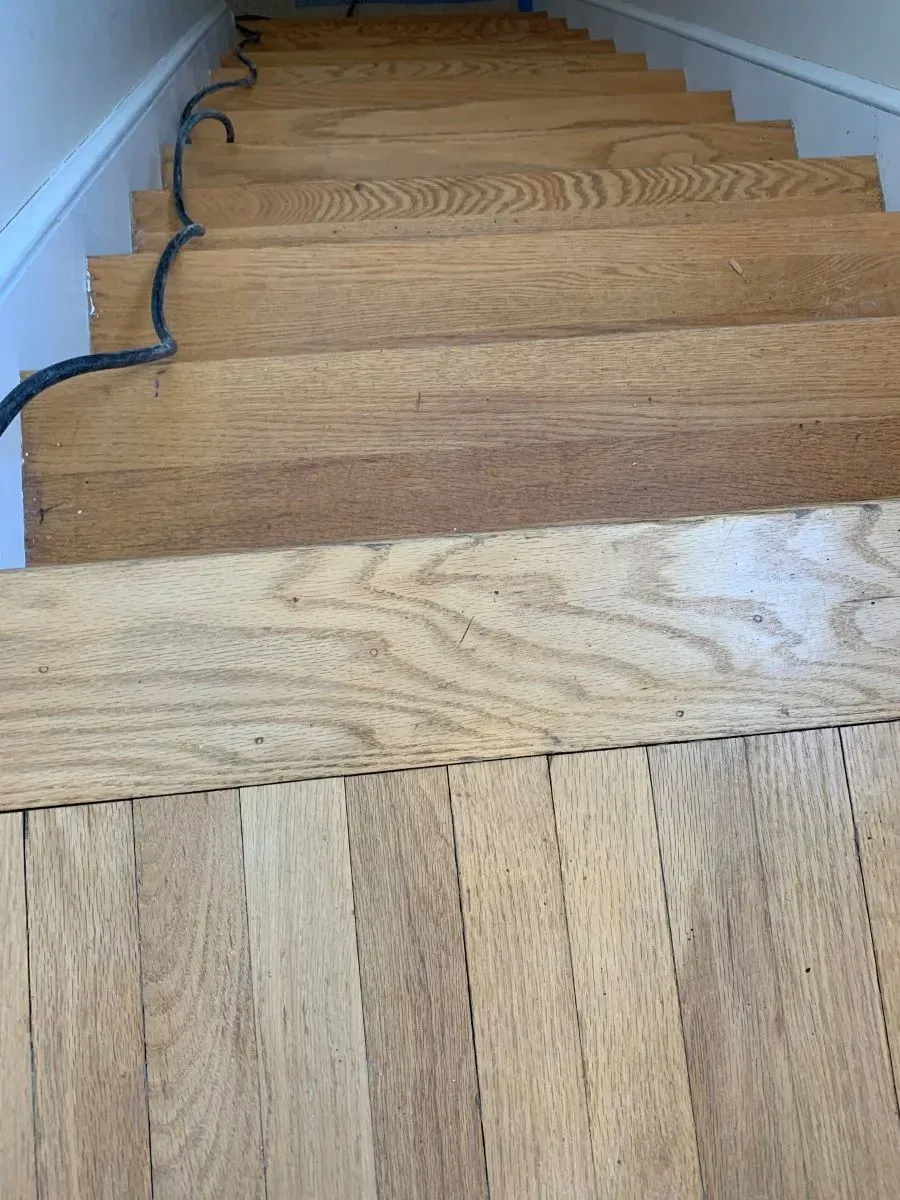 A close up of a wooden staircase with a white railing.