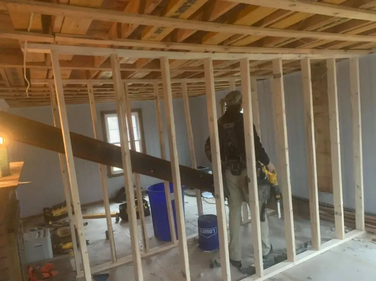 A man is standing in a room with wooden beams.