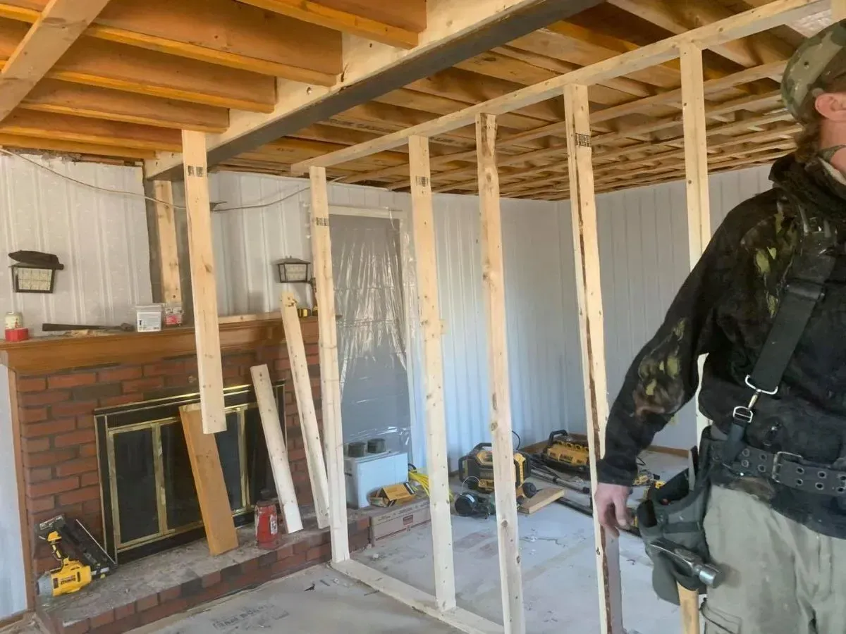 A man is standing in a room with a fireplace in the background.