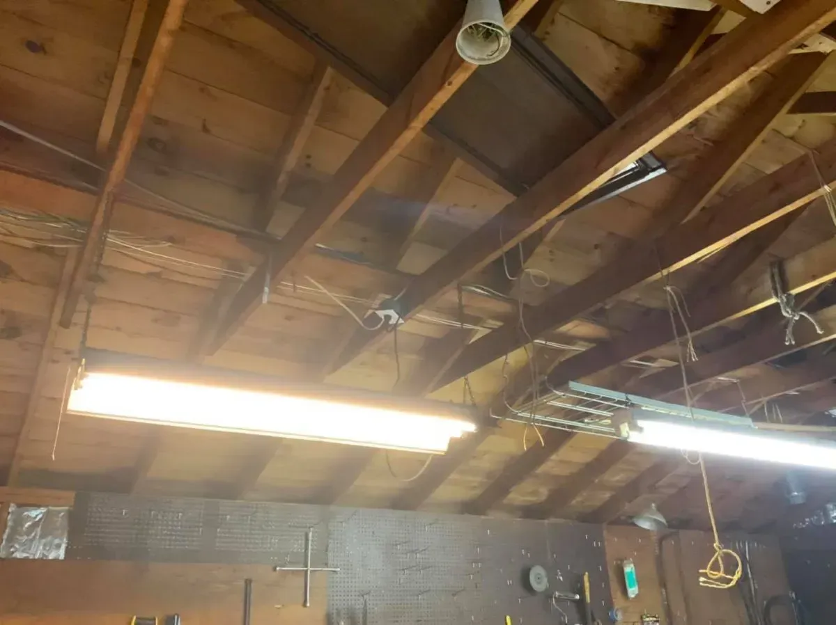 The ceiling of a garage with a light hanging from it.