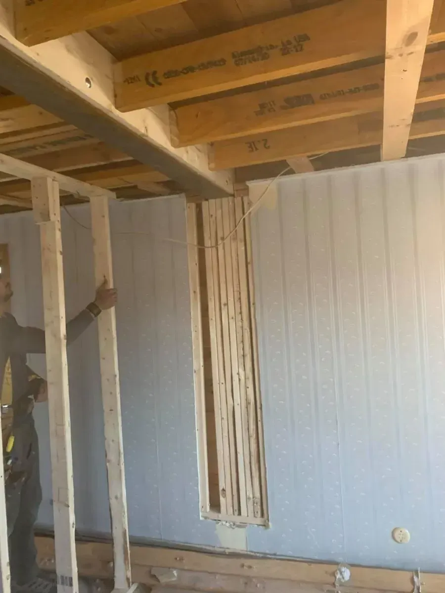 A man is standing in a room with wooden beams.