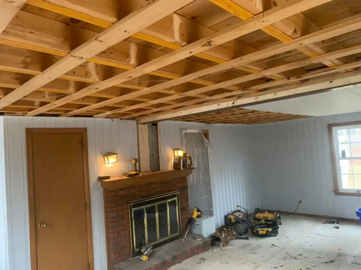 A living room with a fireplace and a wooden ceiling.