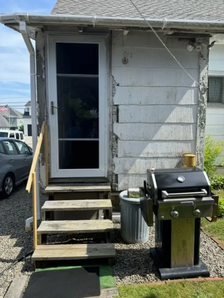A small house with stairs and a grill in front of it