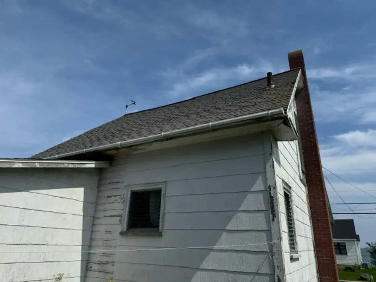 A white house with a brick chimney on the side