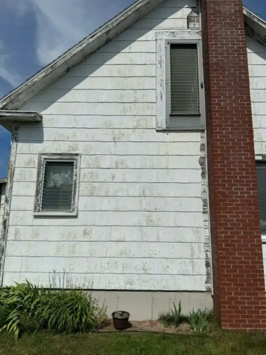 A white house with a brick chimney on the side