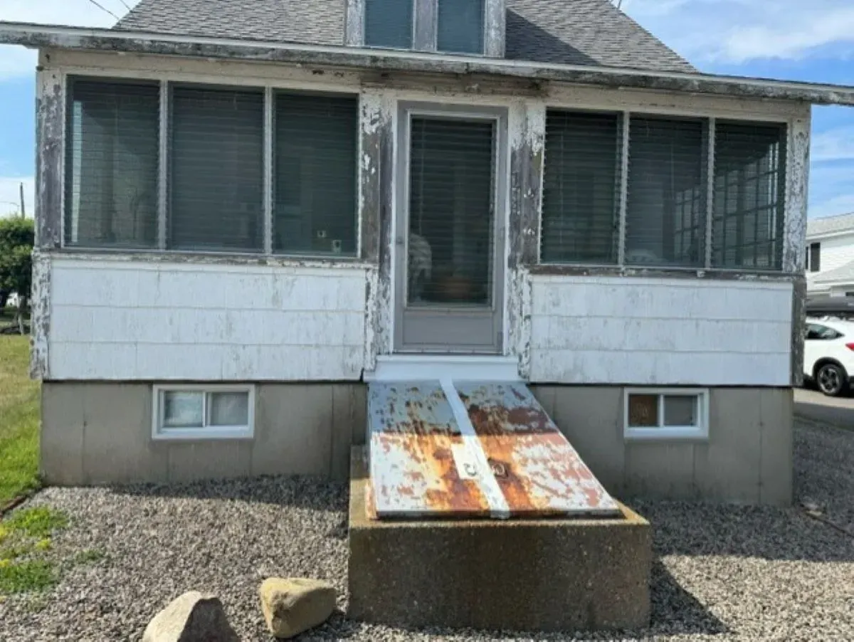 A small house with a screened in porch and a ramp