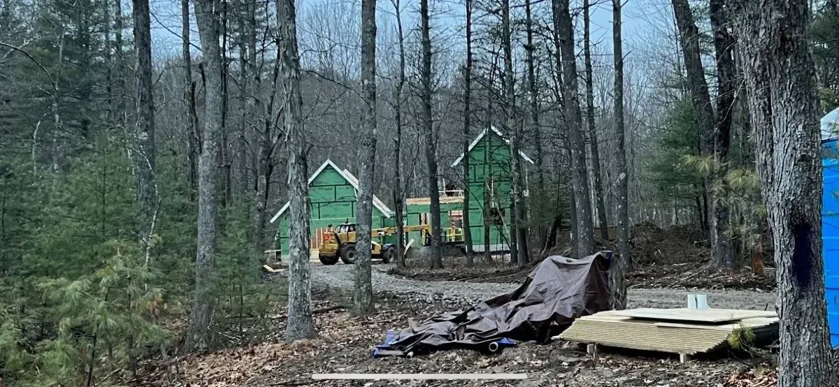 A green house is being built in the middle of a forest.