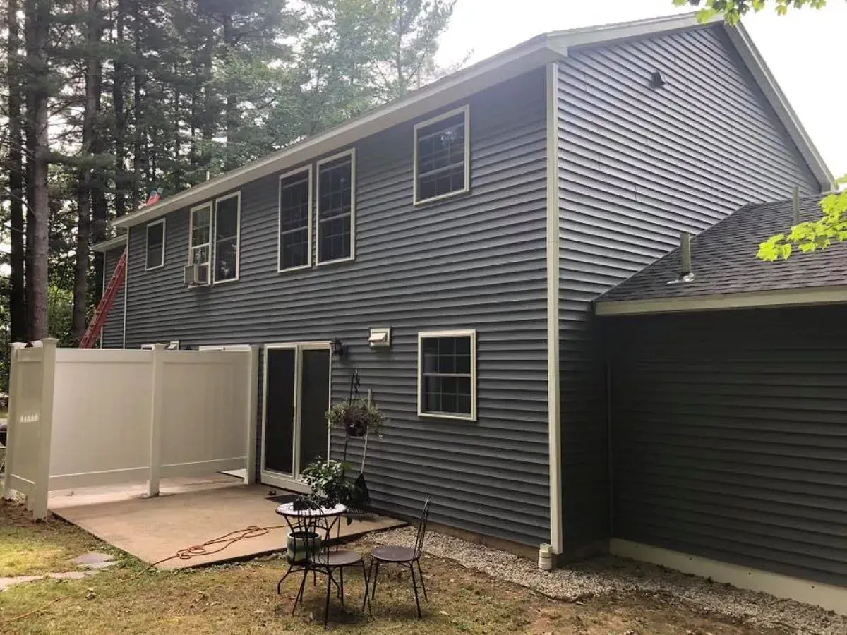 A large house with a fence and a table and chairs in front of it.