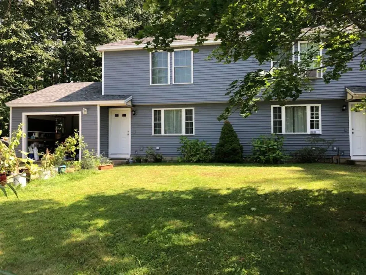 A large house with a garage and a large lawn in front of it.