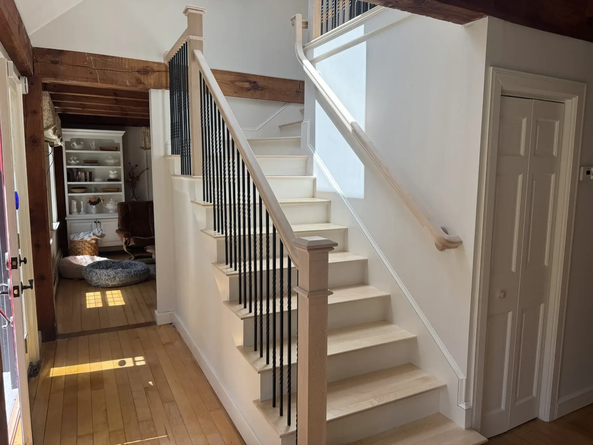 A white staircase with a black railing in a hallway