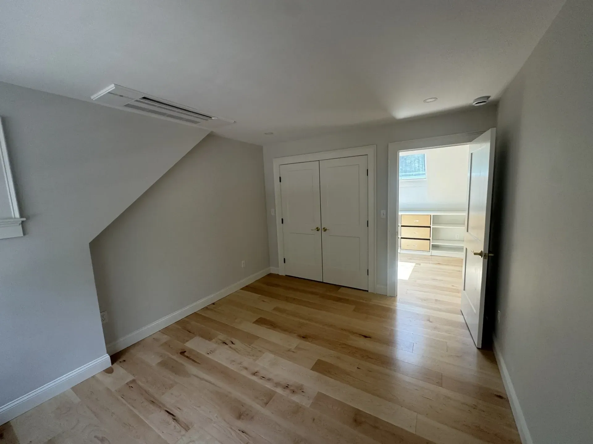 An empty room with hardwood floors and white walls.