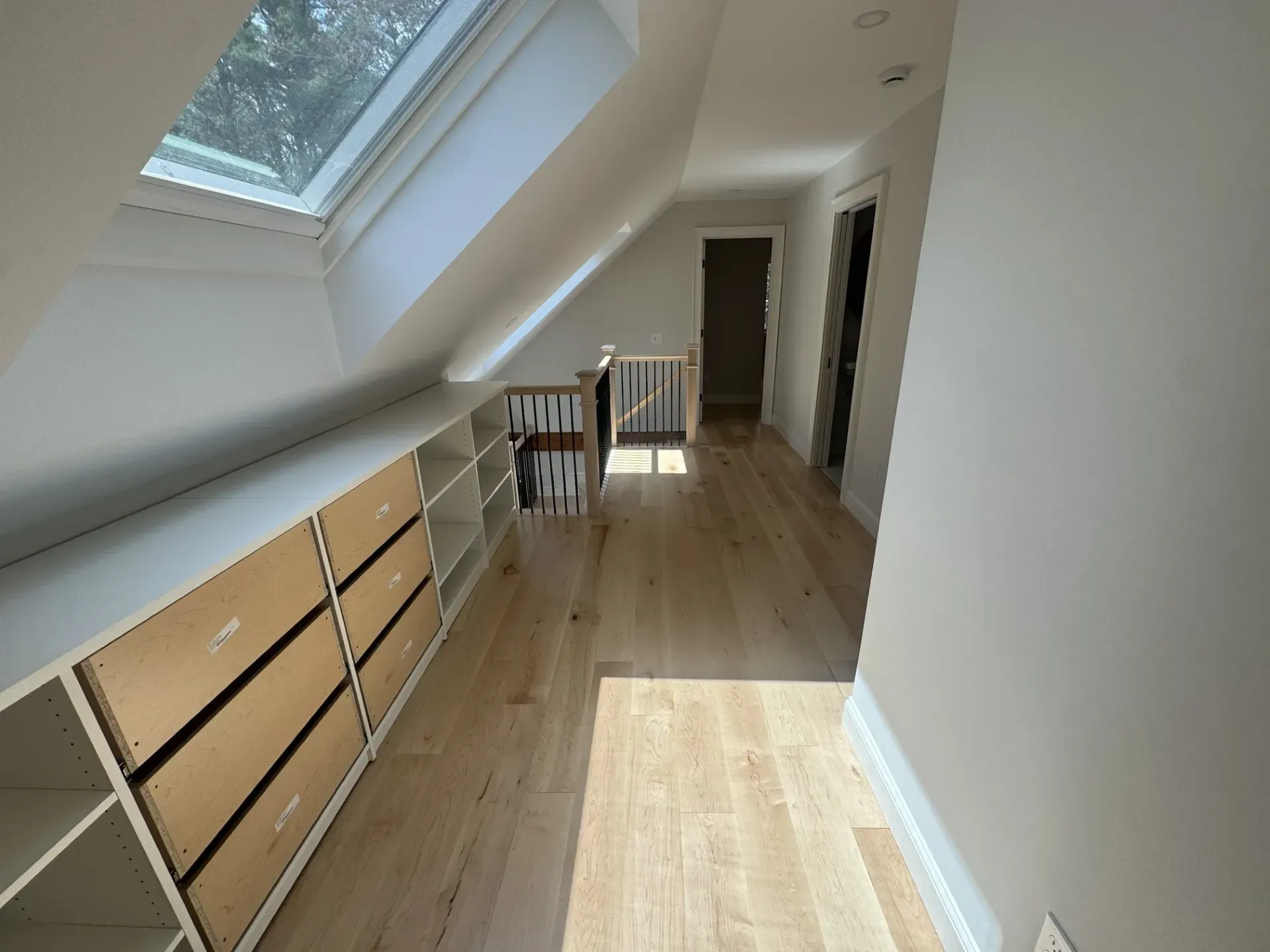A hallway with a staircase and a skylight in the ceiling