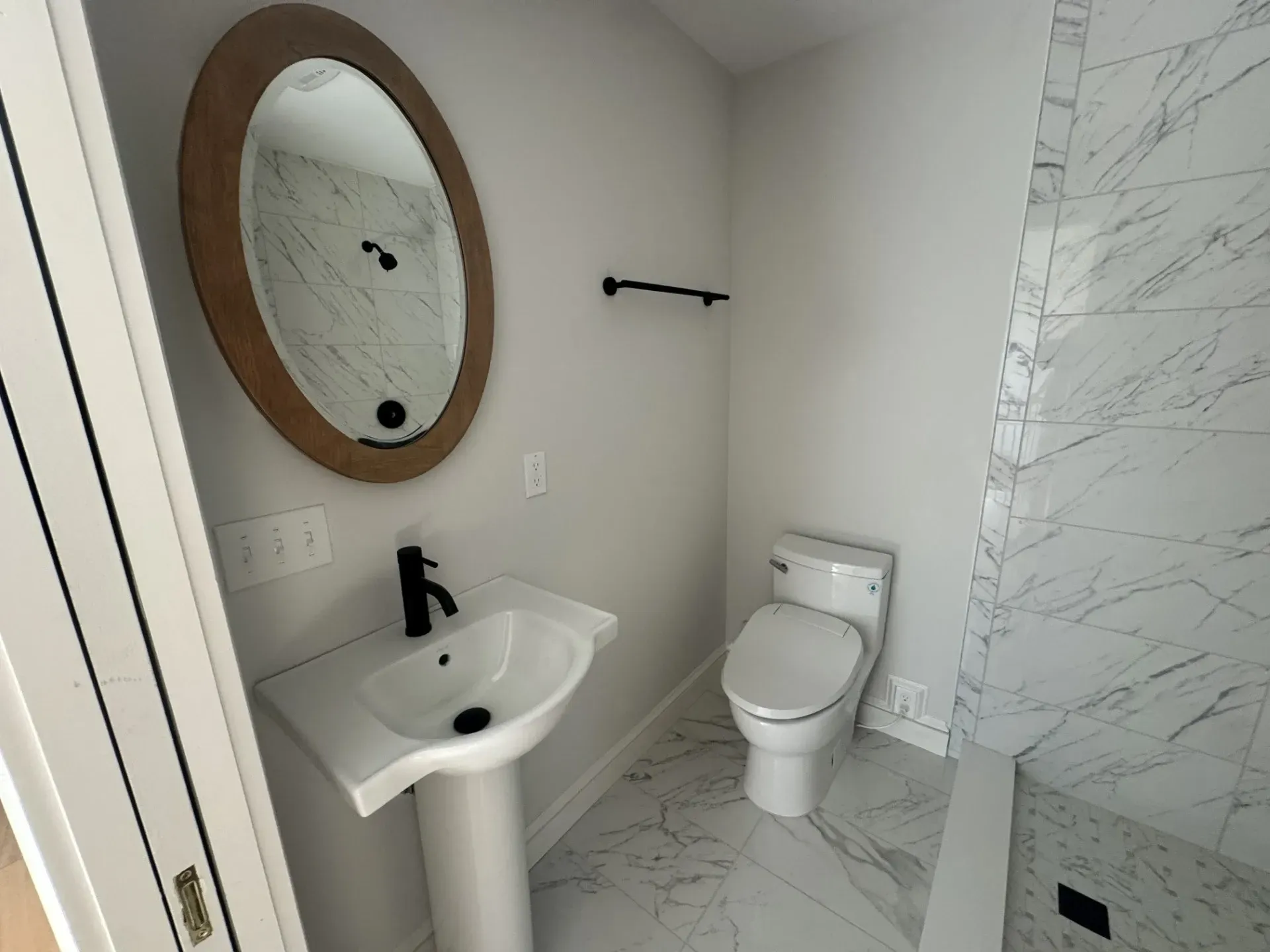 A bathroom with a toilet , sink and mirror.