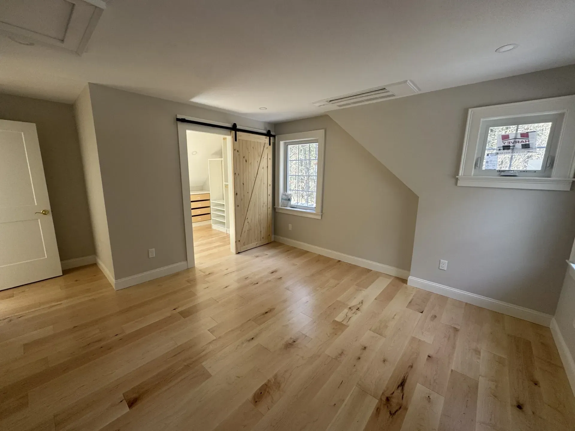 An empty room with hardwood floors and a sliding barn door.