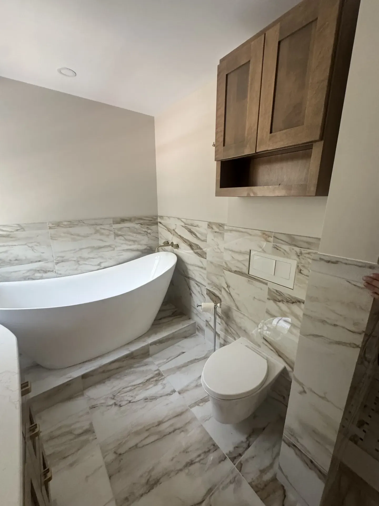 A bathroom with a bathtub , toilet , and cabinets.