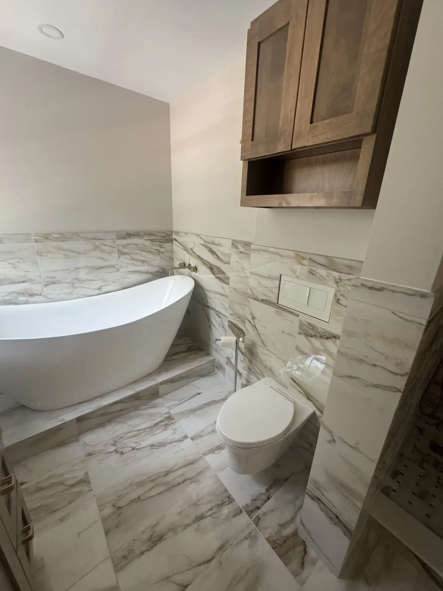 A bathroom with a tub , toilet , and cabinets.