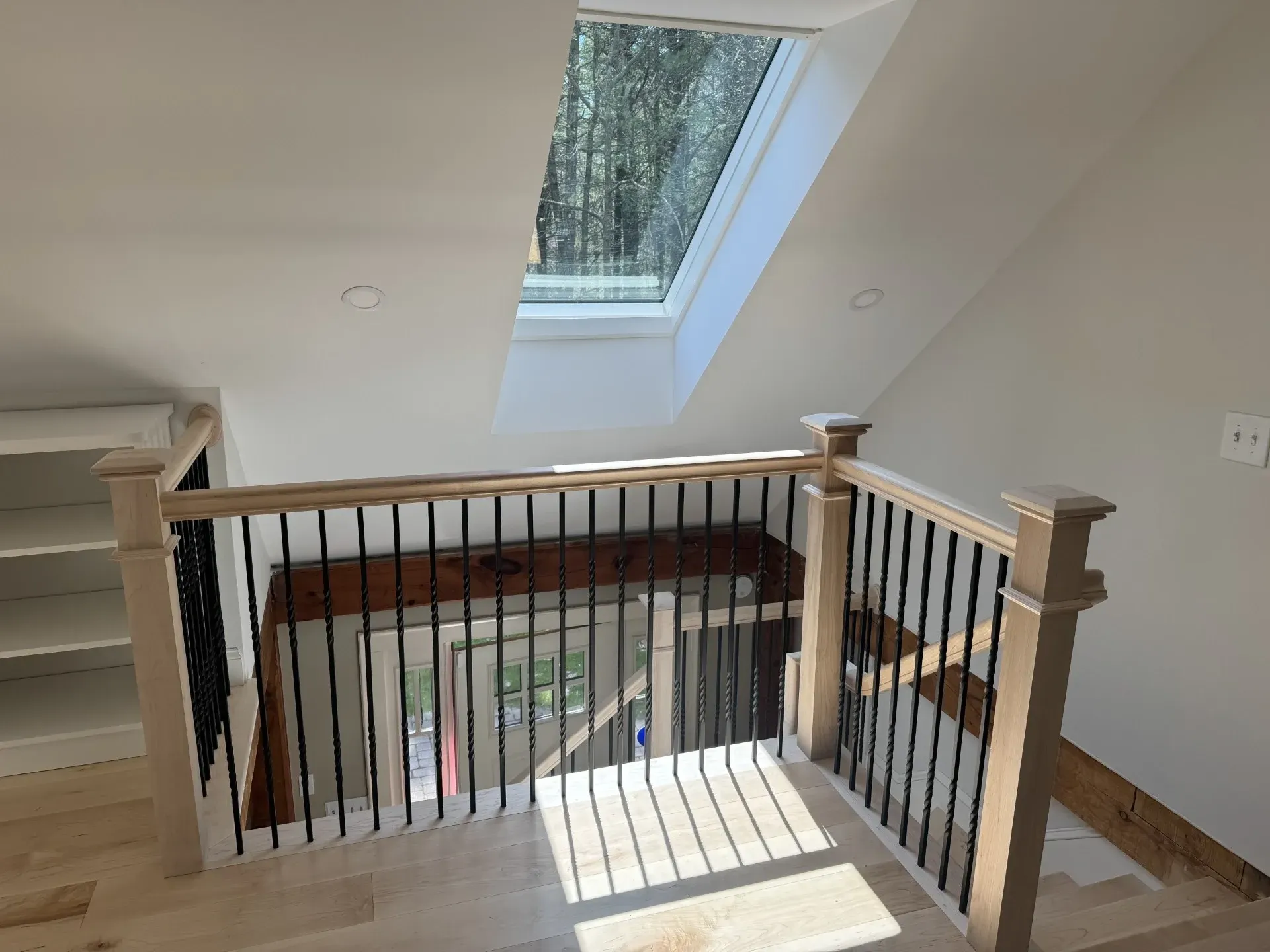 A staircase with a wooden railing and a skylight in the ceiling.
