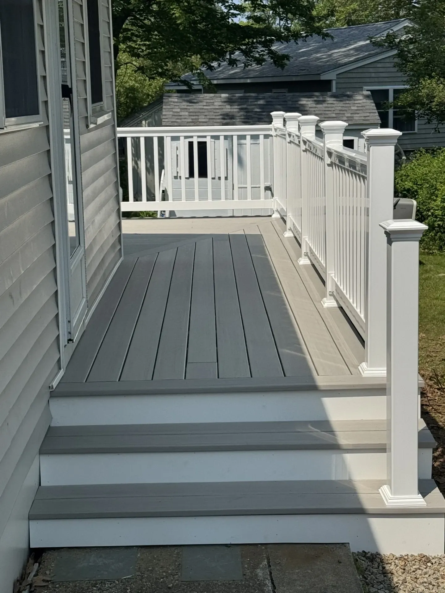 A deck with stairs and a white railing on the side of a house