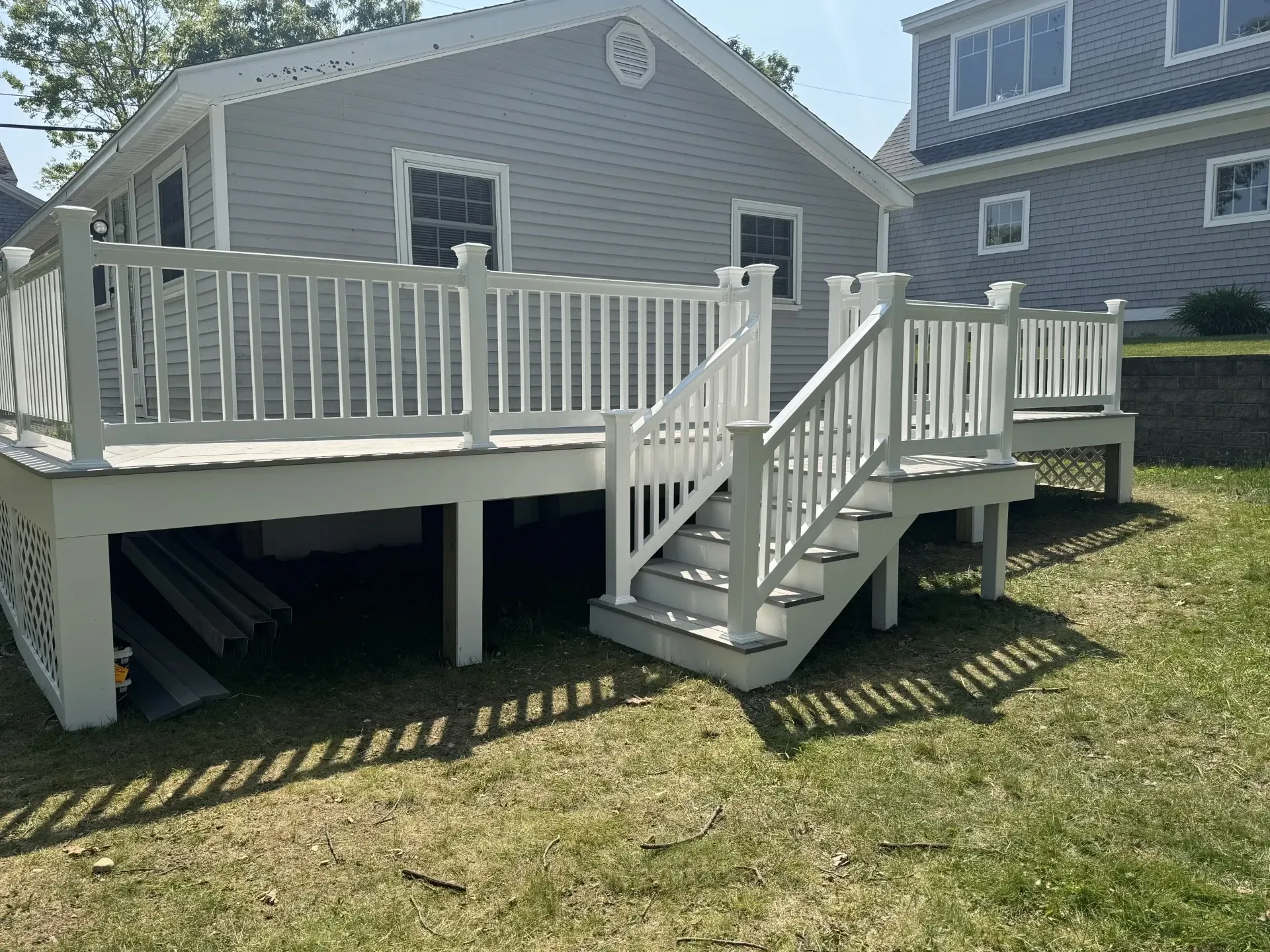 A white deck with stairs leading up to it is in front of a house.
