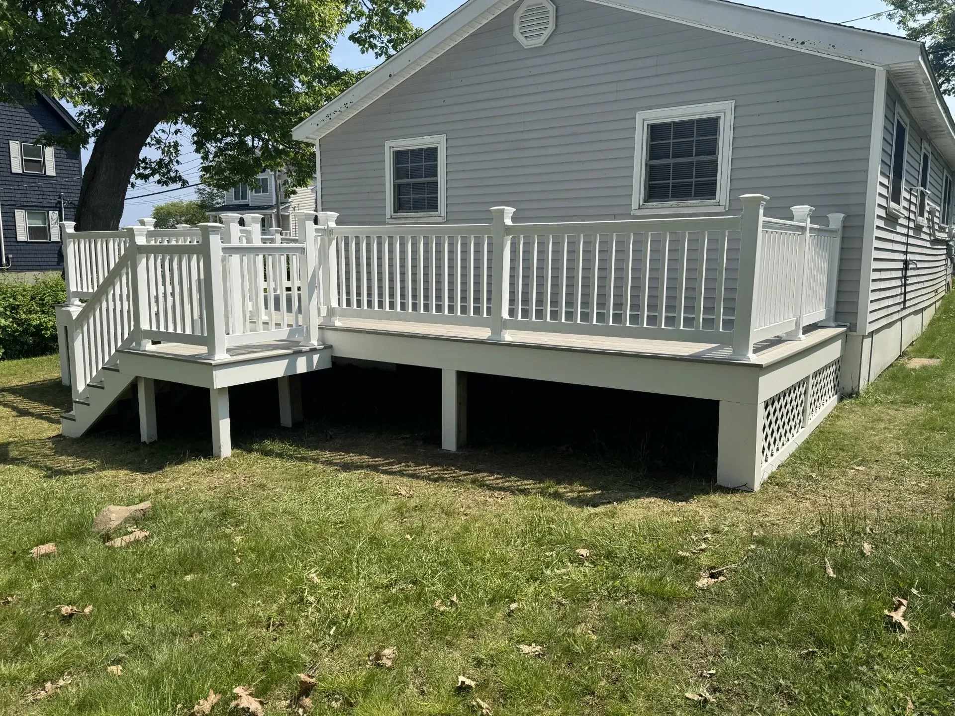 A small white house with a large white deck and stairs.