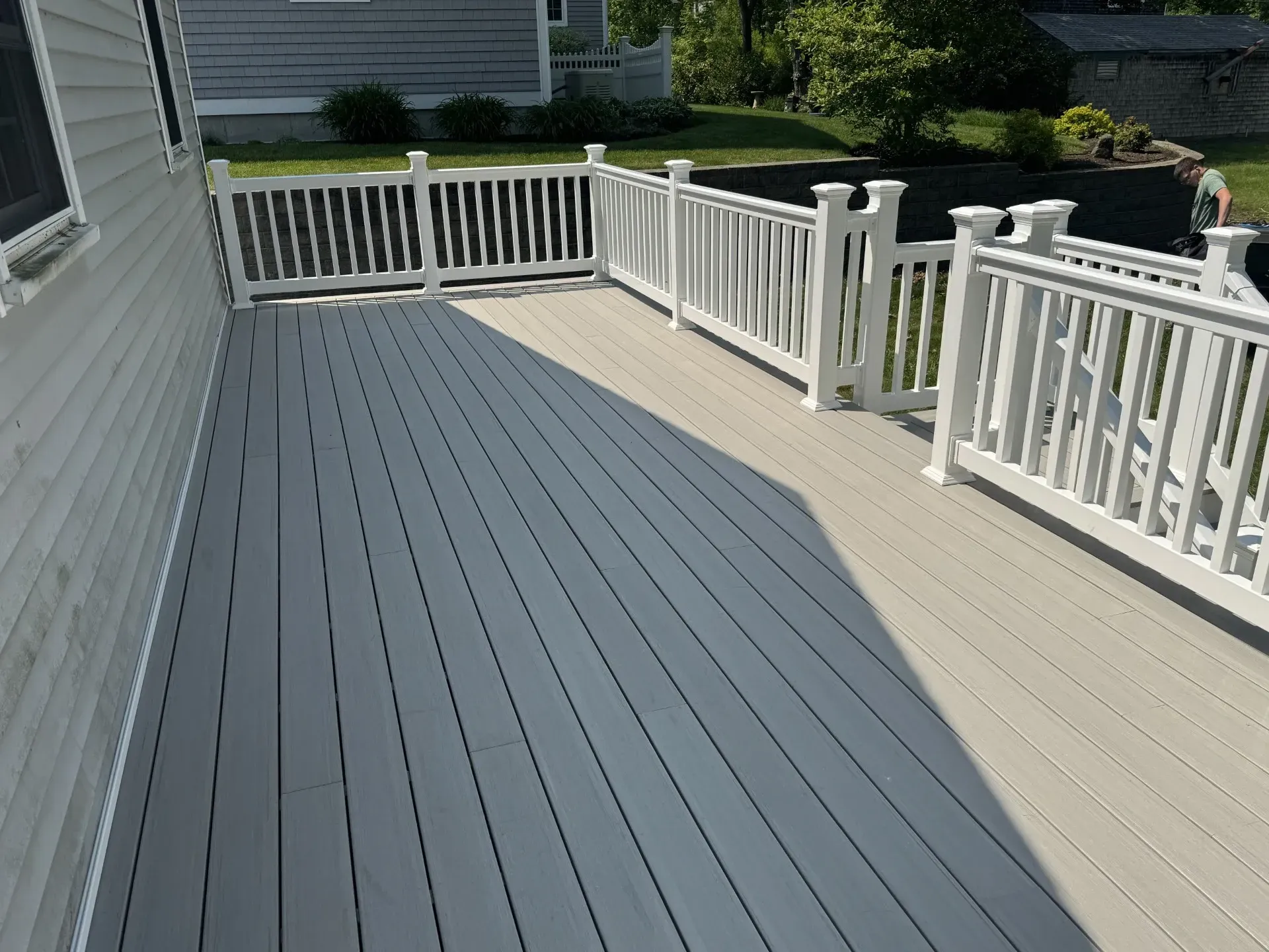 A deck with a white railing and a shadow on it