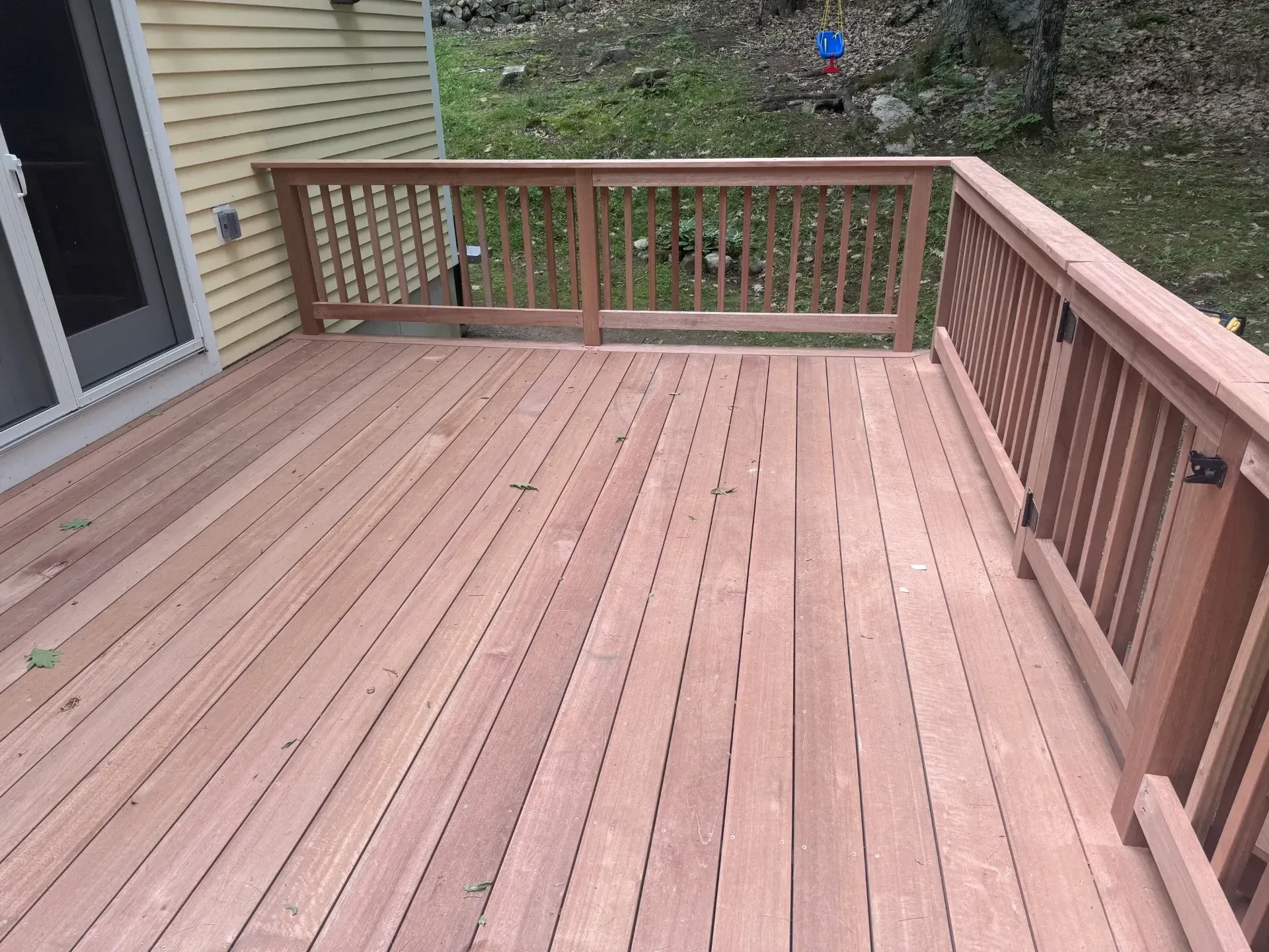 A wooden deck with a railing and a sliding glass door.