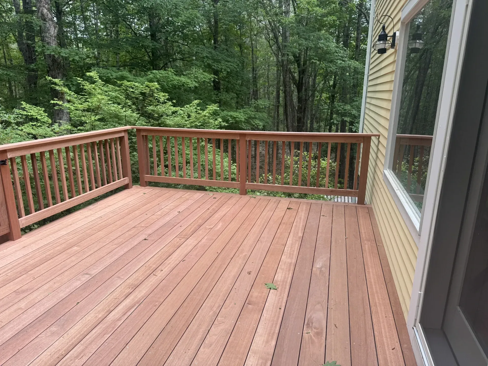 A wooden deck with a railing and trees in the background