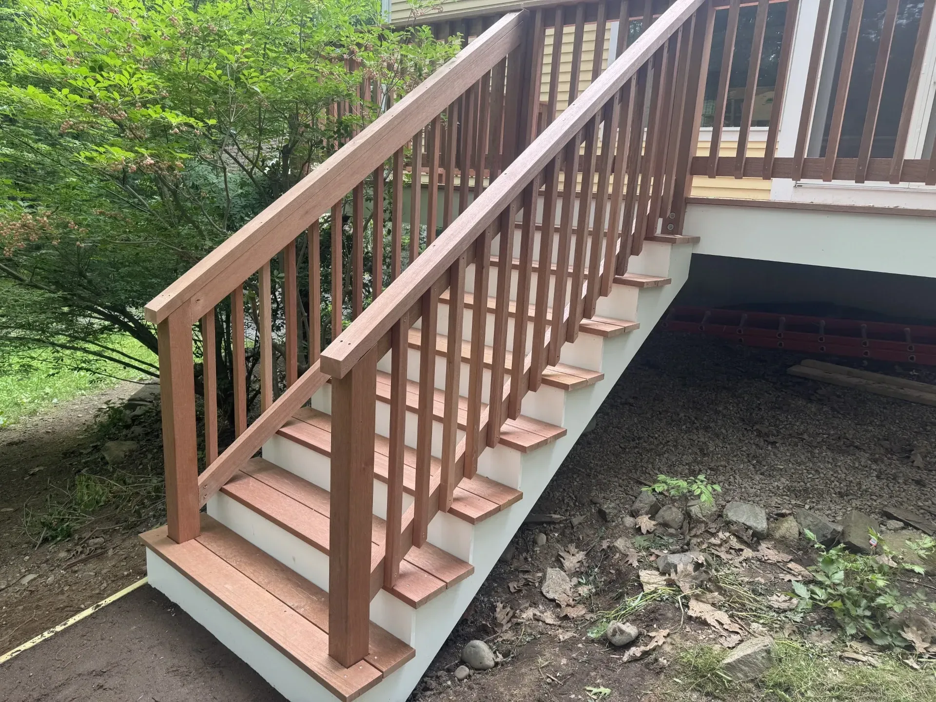 A wooden staircase leading up to a deck with a wooden railing.