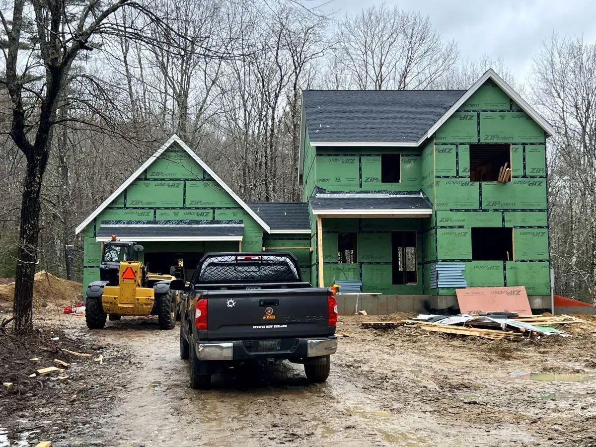 A truck is parked in front of a house under construction.