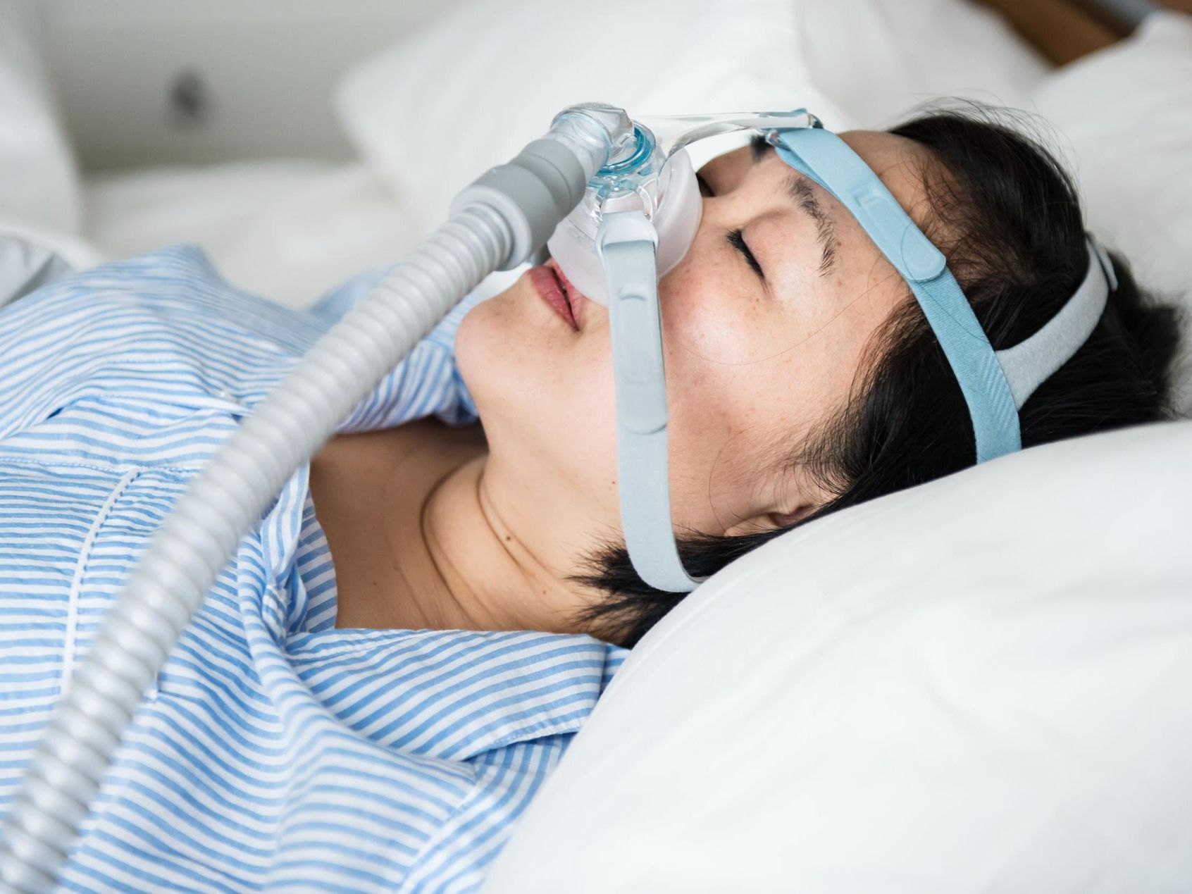 A woman is laying in bed with an oxygen mask on her face.