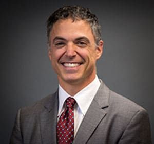 A man in a suit and tie is smiling for the camera.