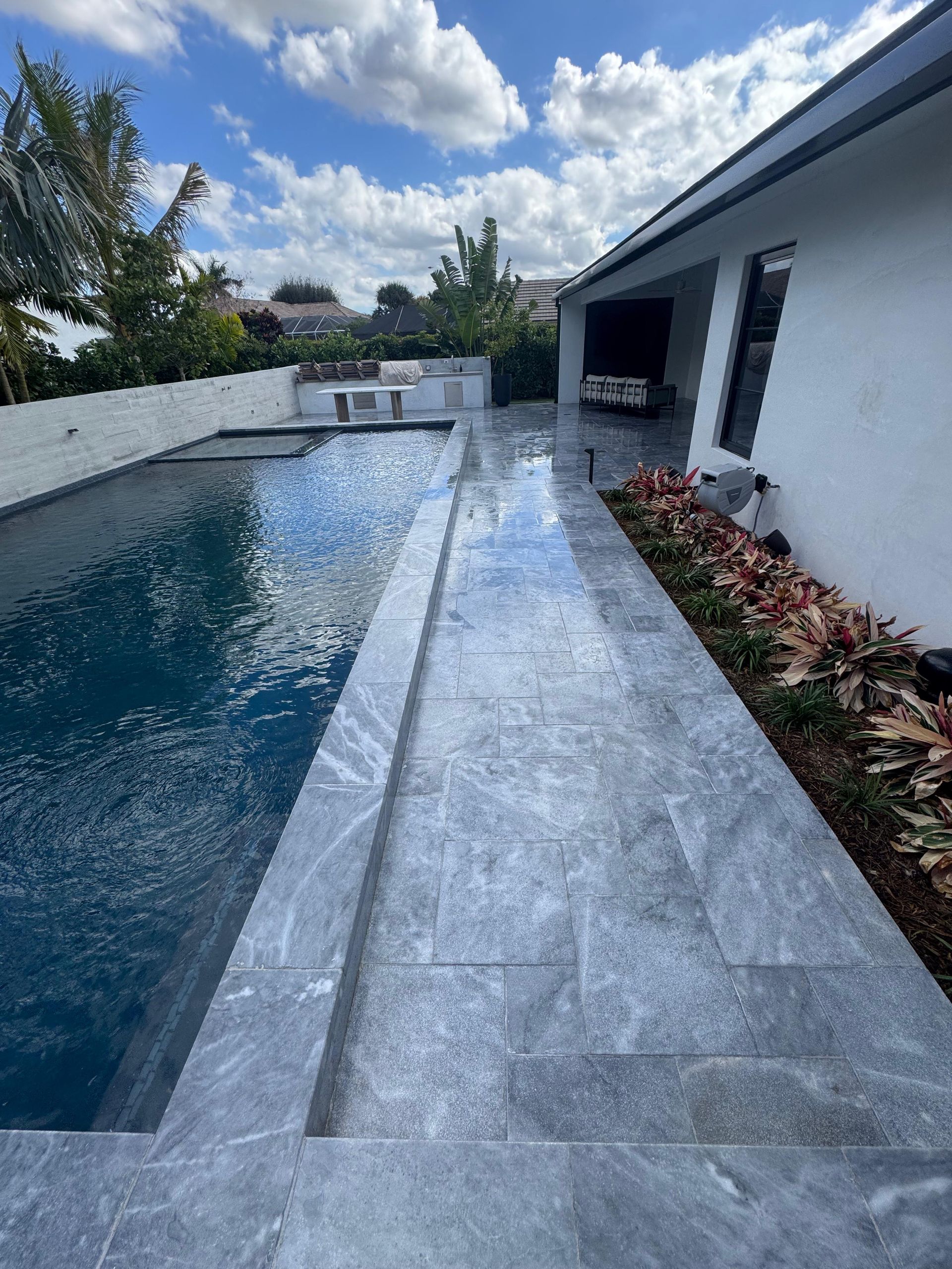 A large swimming pool is in the backyard of a house.