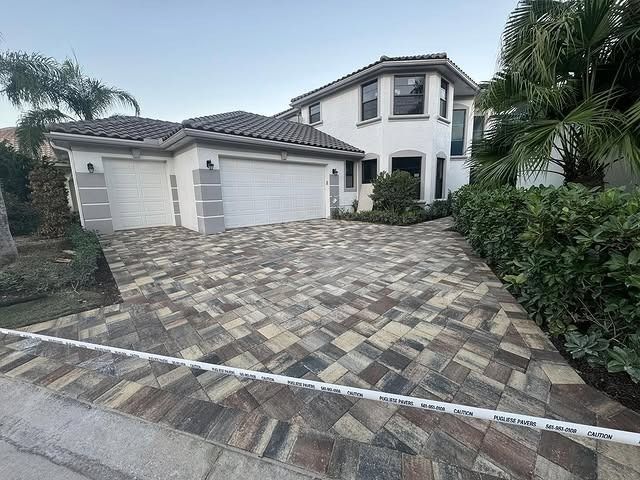 A large white house with a brick driveway in front of it.