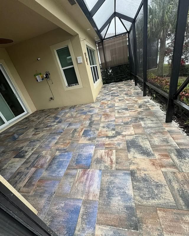 A patio with a screened in porch and a ceiling fan.