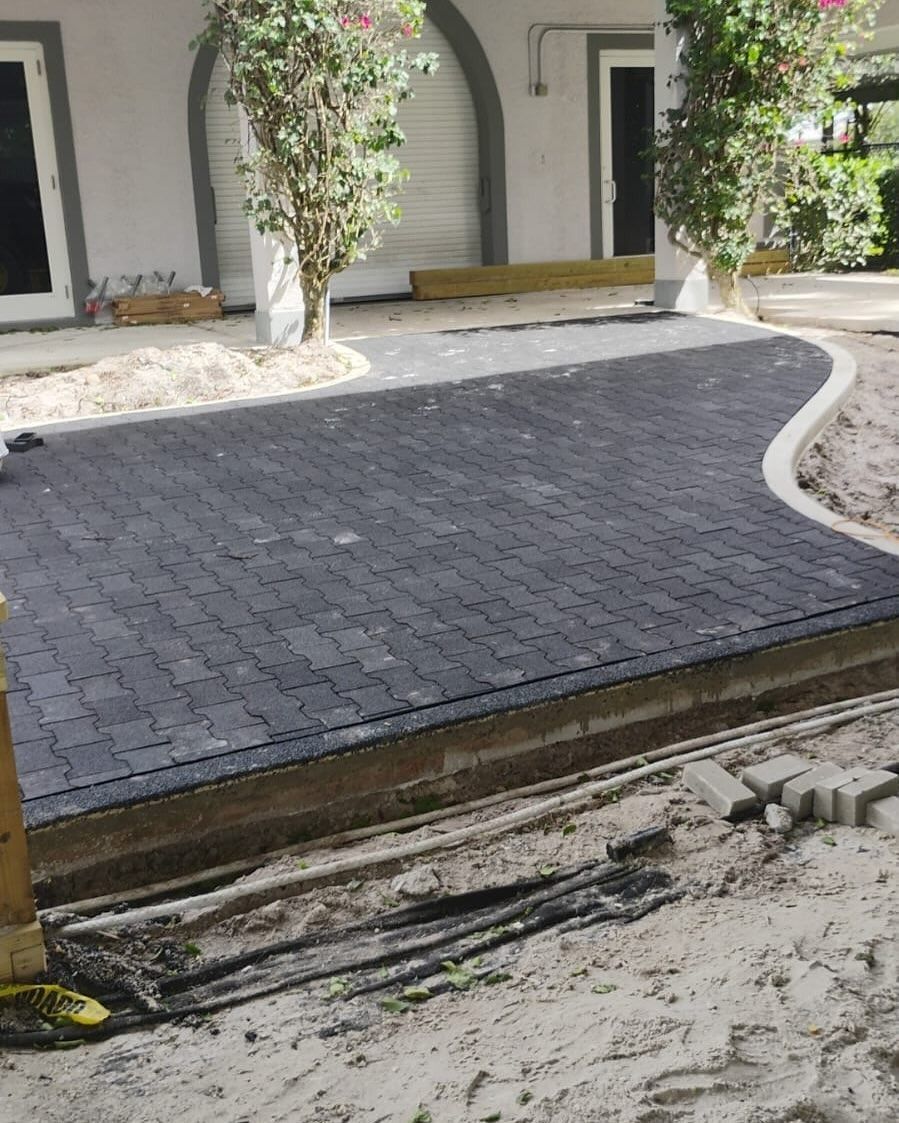 A brick driveway is being built in front of a house.