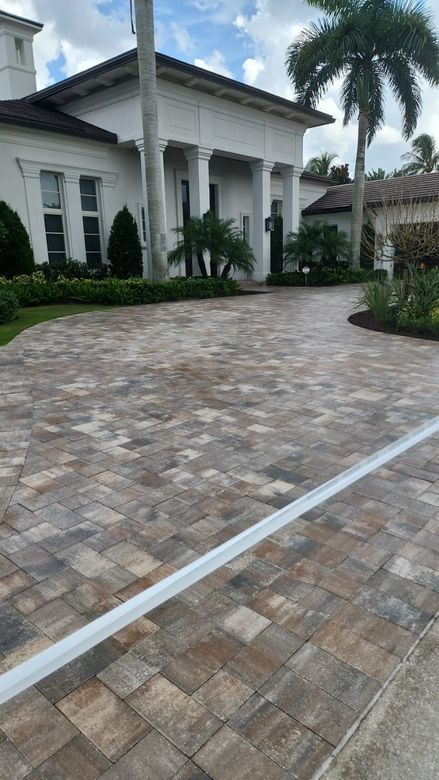 A large white house with a brick driveway in front of it.