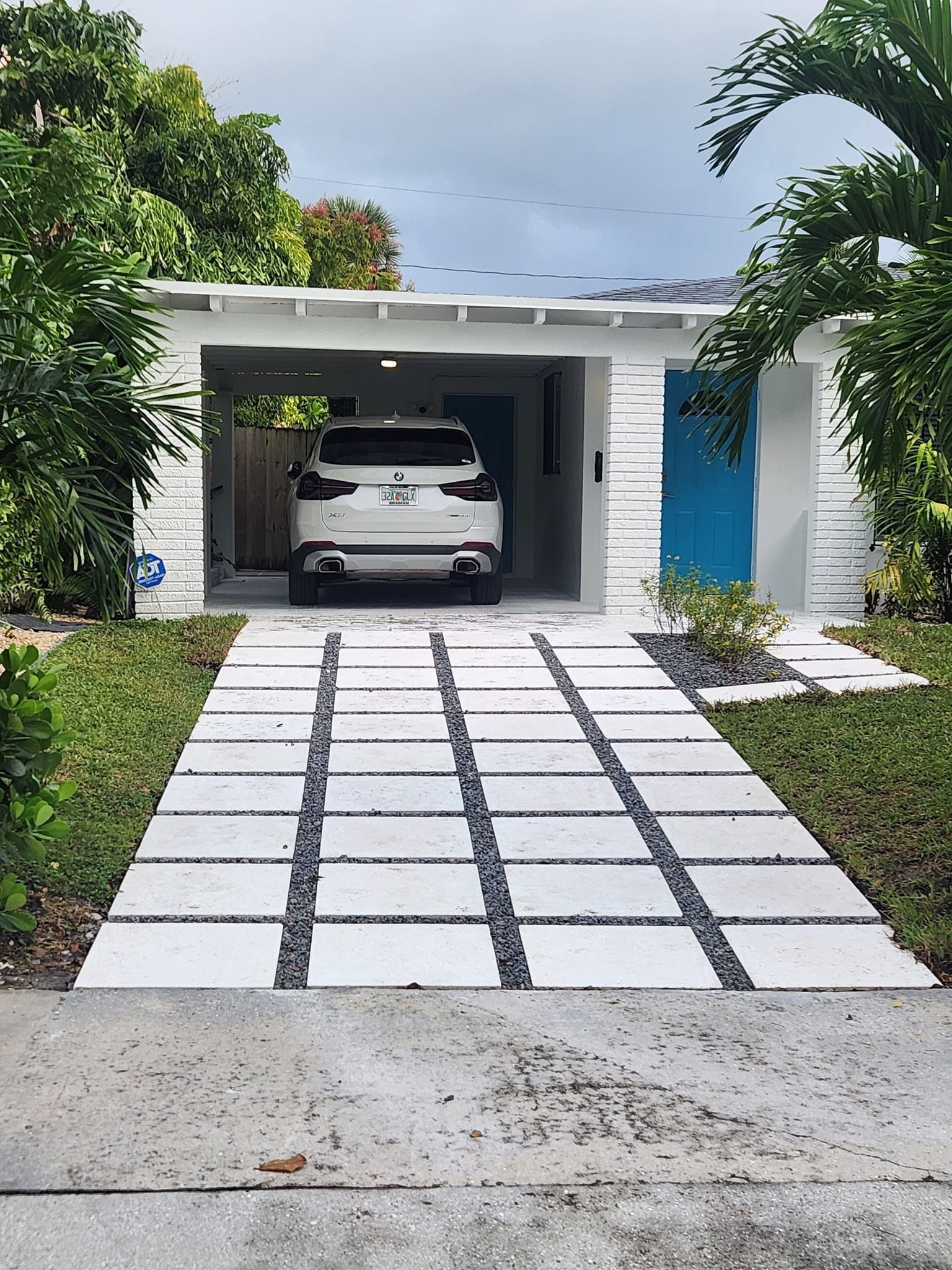 A white car is parked in the driveway of a house.