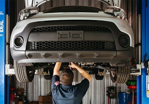 Mechanic working underneath a car on a lift in a garage.