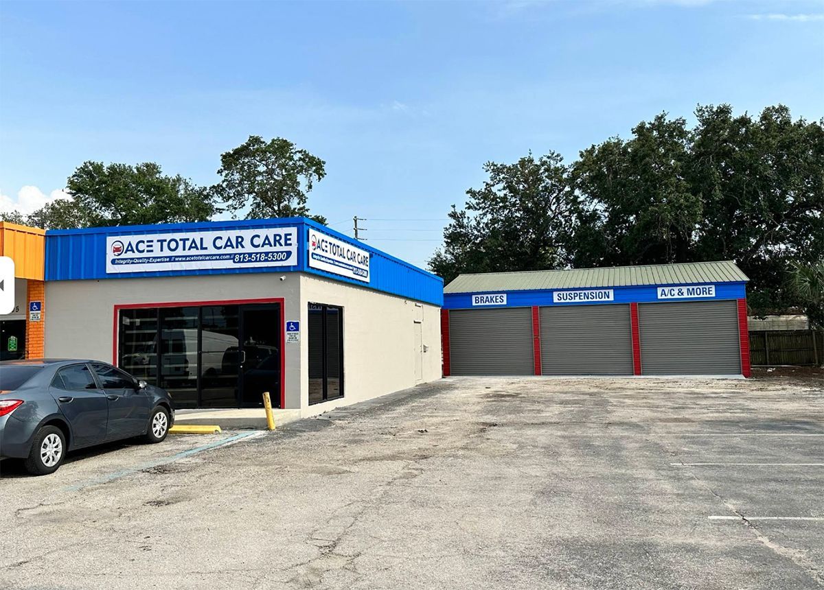 Auto repair shop with blue and tan exterior, a gray car parked out front.