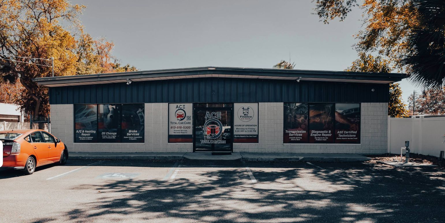 A small, one-story building with large windows, a parking lot, and an orange car parked out front.