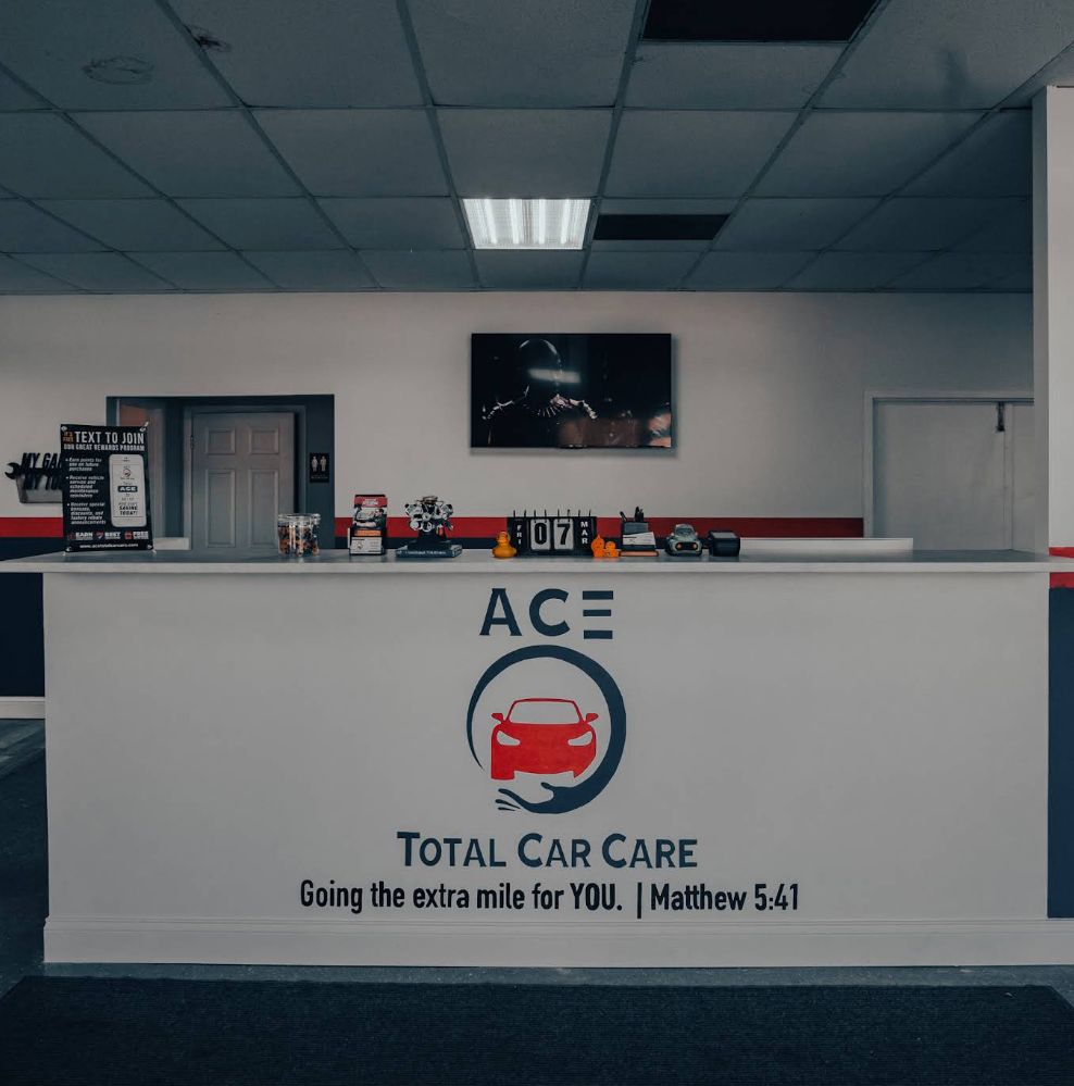 Reception desk at Ace Total Car Care with logo; red, white, and blue accents.
