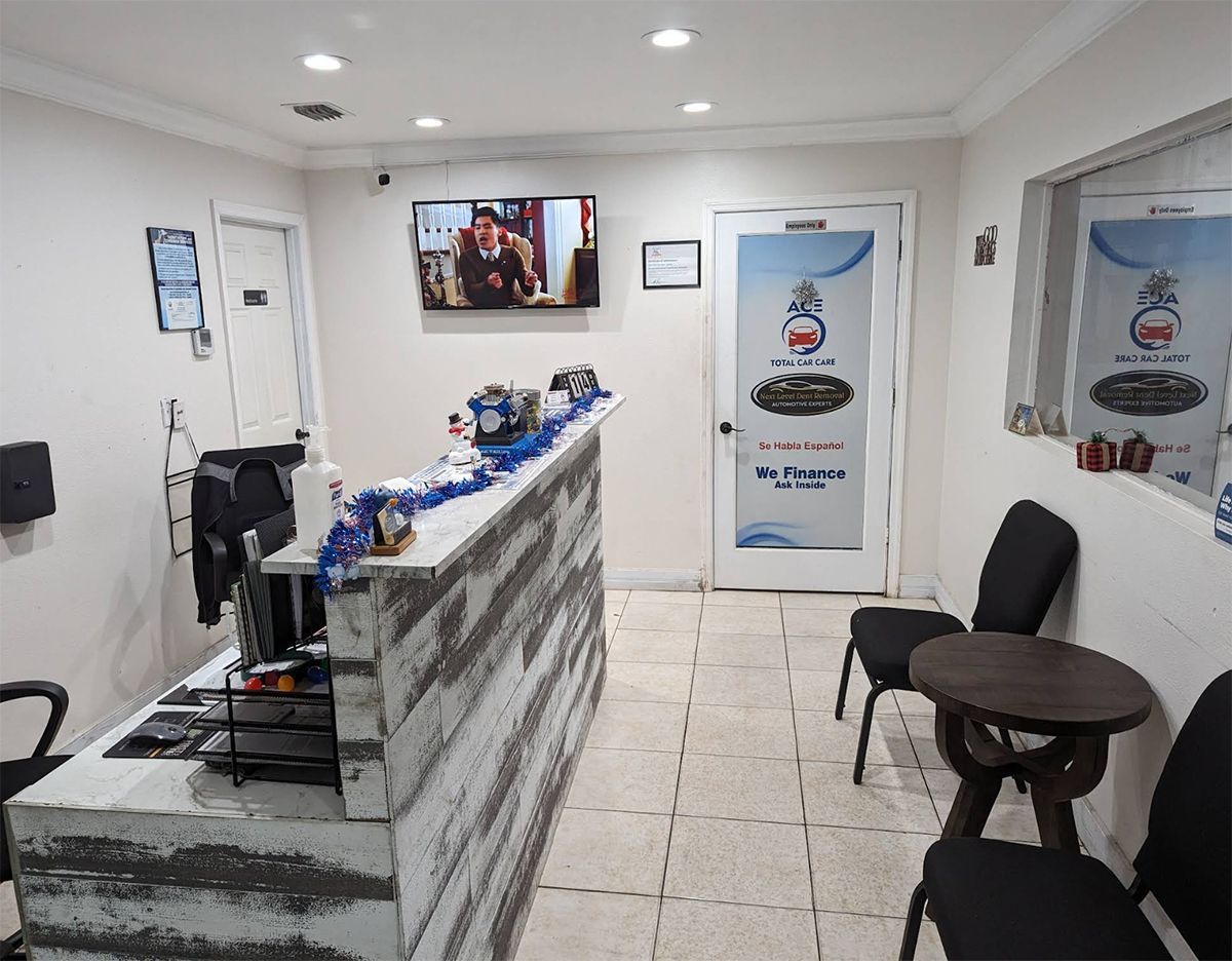 Reception area with rustic desk, chairs, and television. Door to the left and a window with a sign to the right.