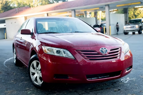 Red Toyota Camry parked at a car wash.
