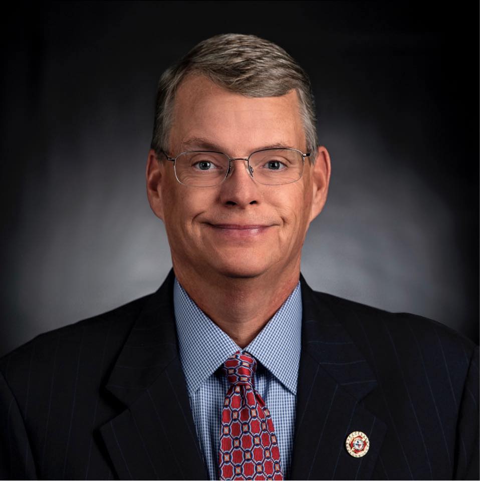 A man in a suit and tie is smiling for the camera