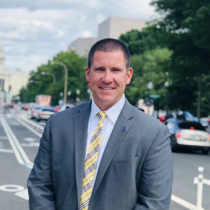 A man in a suit and tie is standing on a street