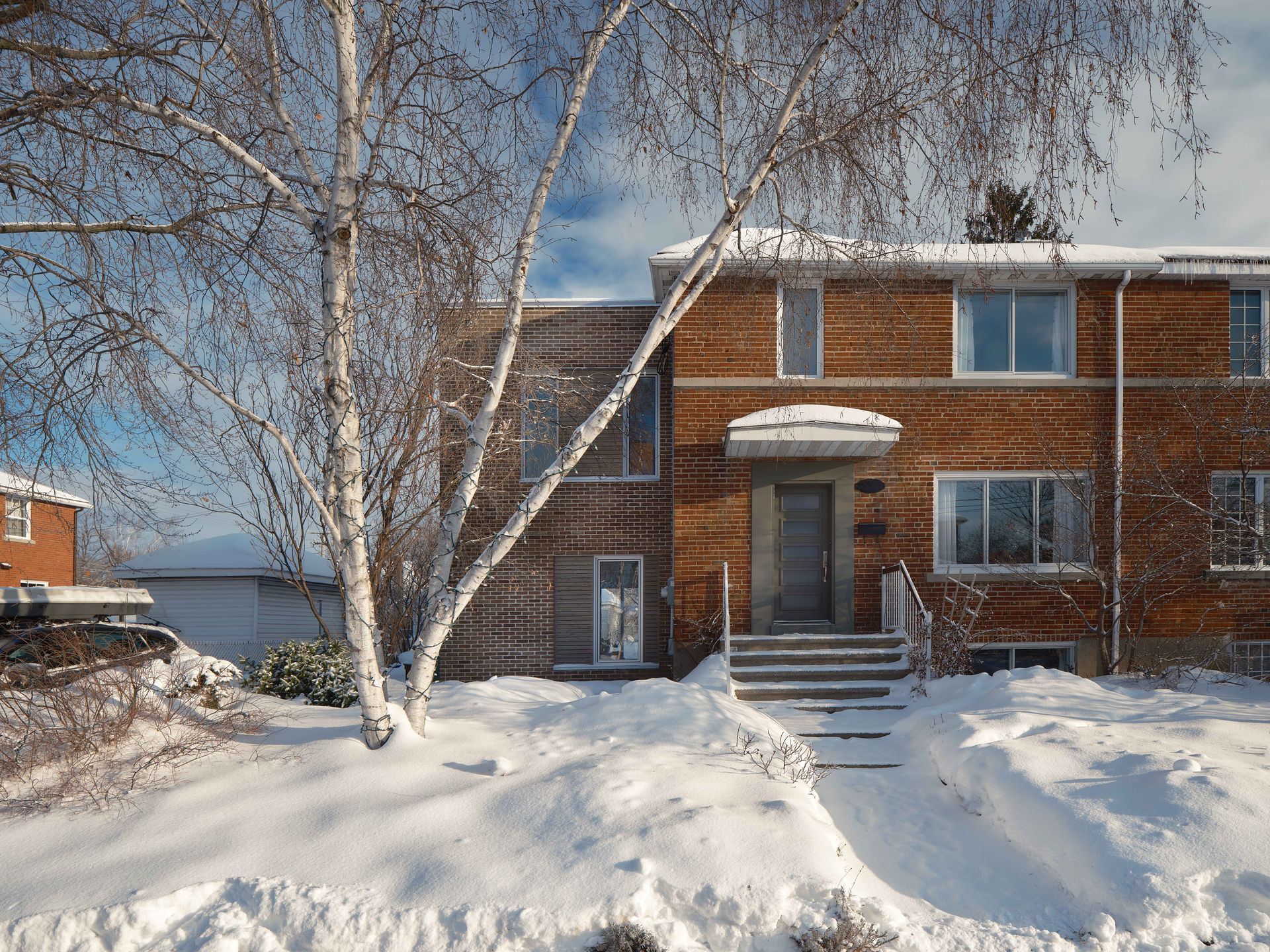 Une maison en briques avec de la neige sur le sol devant elle