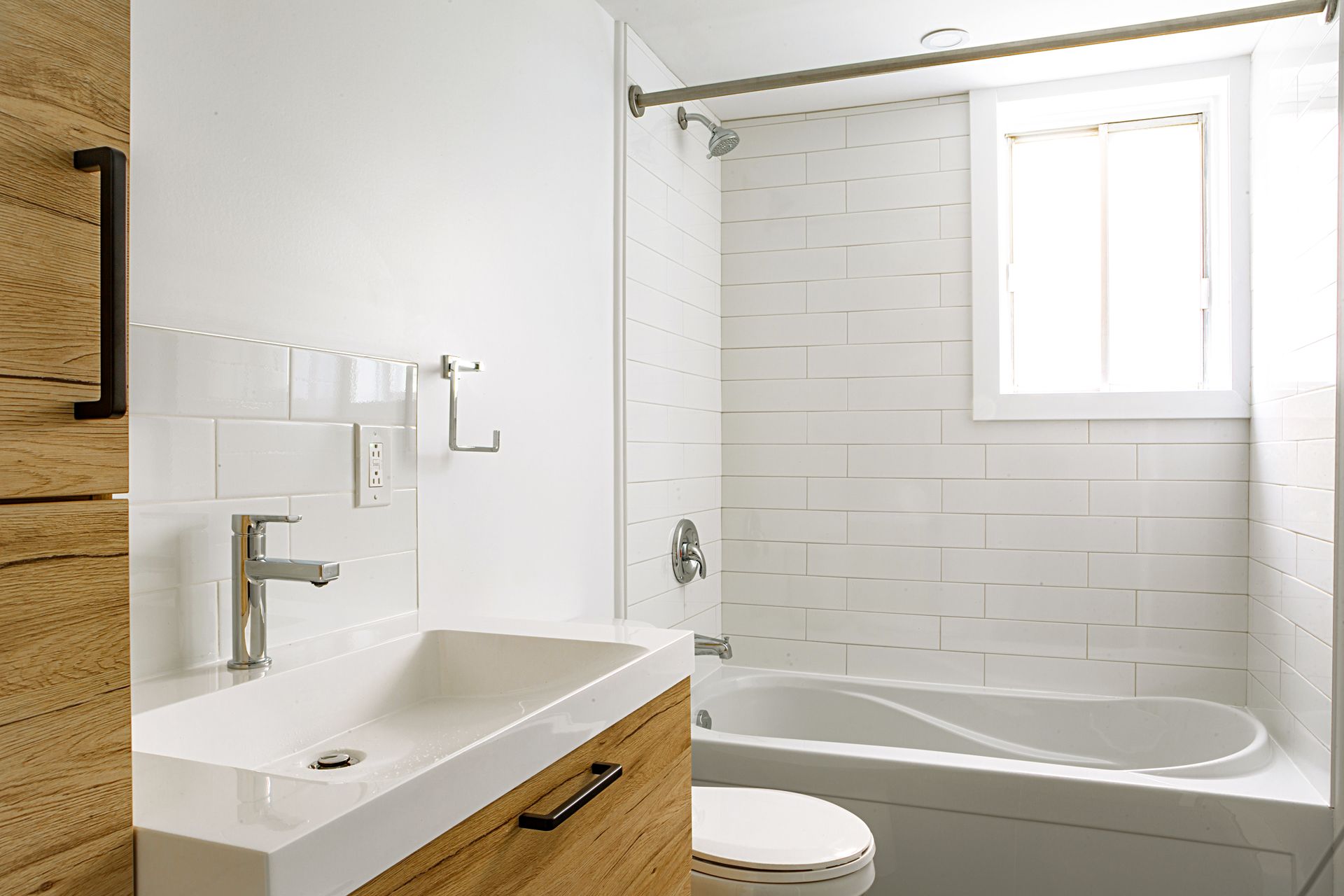 Une salle de bain avec lavabo, toilettes, baignoire et fenêtre.