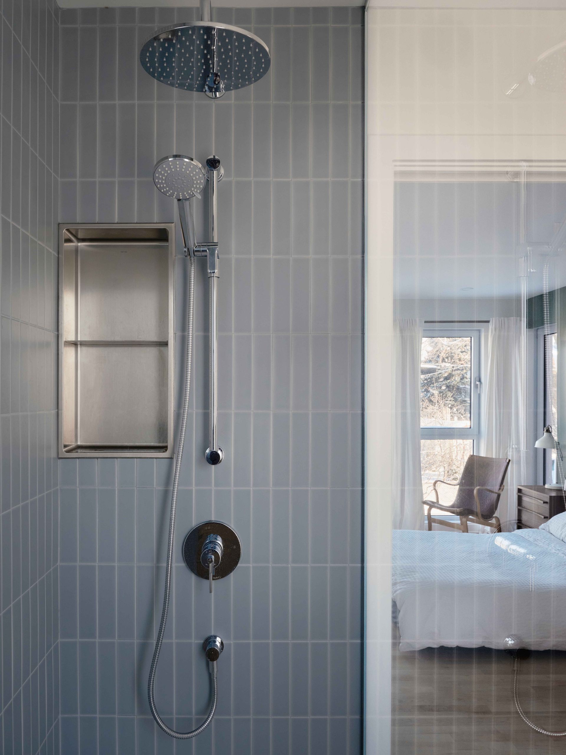 Une salle de bain avec douche et un lit en arrière plan.