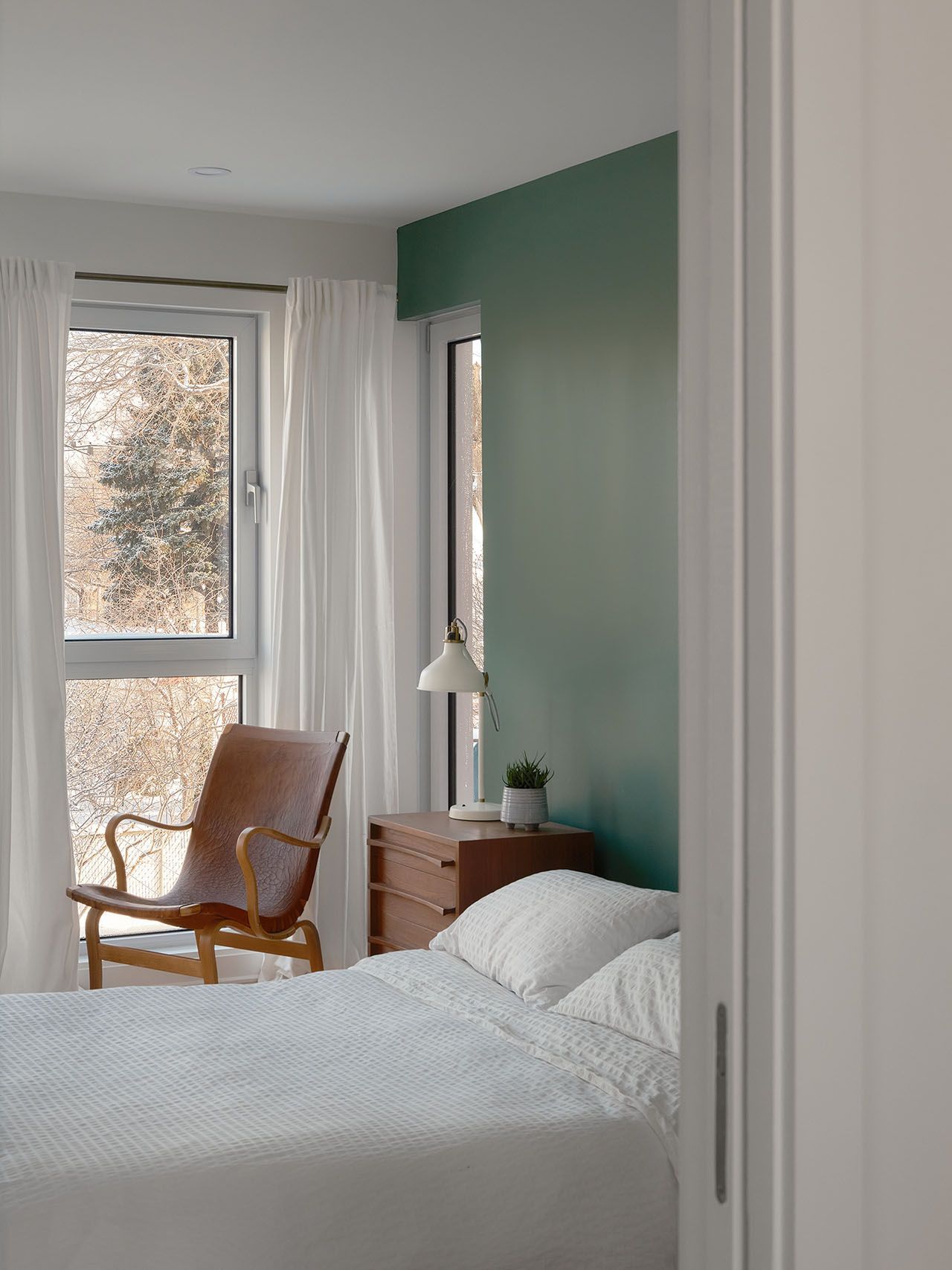 Une chambre avec un lit, une chaise, une table de chevet et une fenêtre.