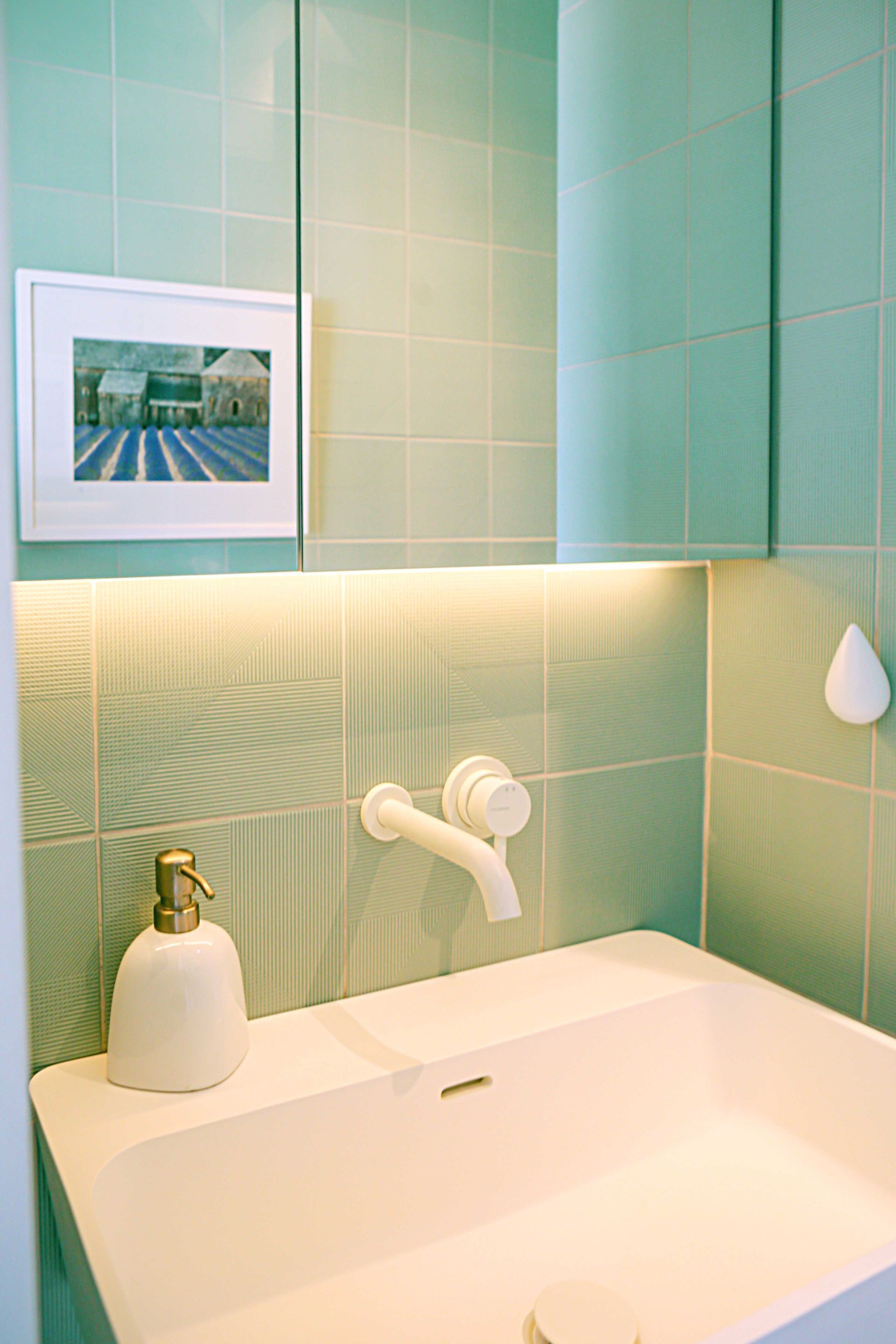 Un lavabo de salle de bain avec un tableau sur le mur au-dessus.